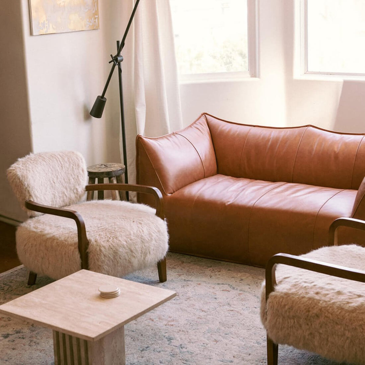 Living room with brown leather sofa, white armchairs, and a wooden coffee table.